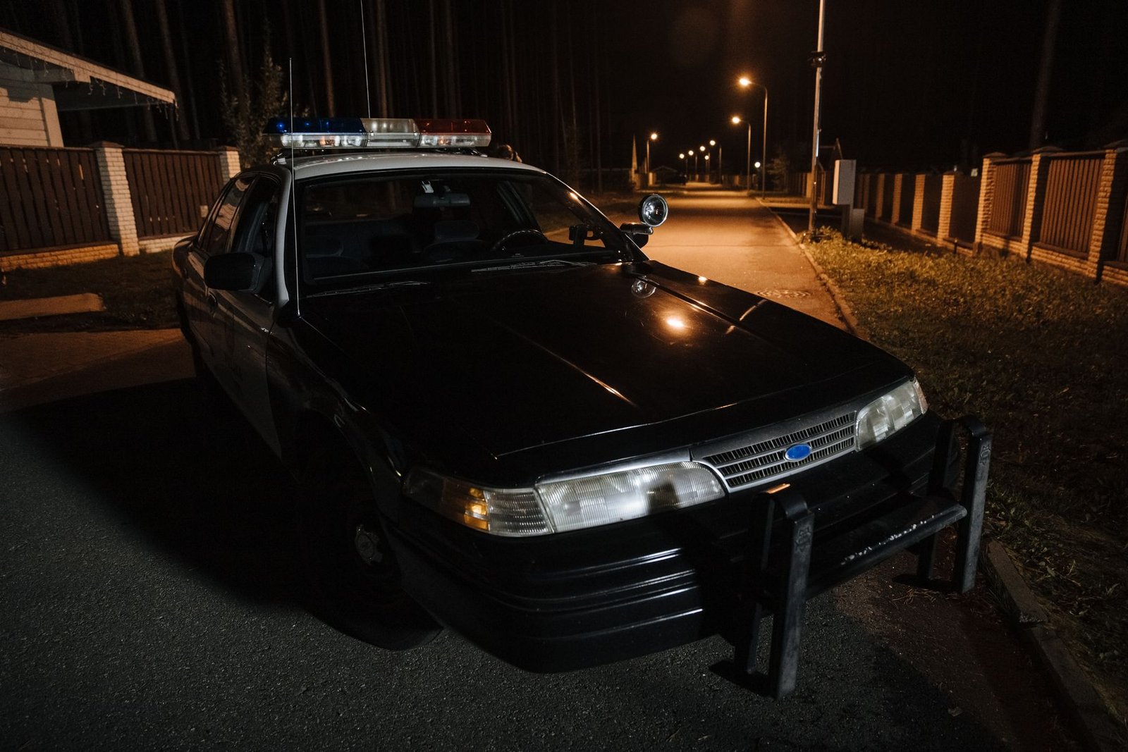 Viatura policial estacionada em rua durante a madrugada, com giroflex aceso