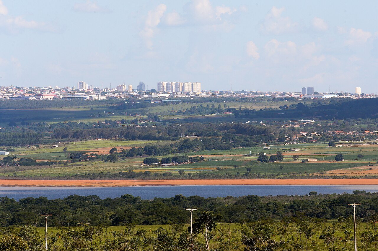 Vista do reservatório do Descoberto, com vegetação nas margens e área urbana ao fundo