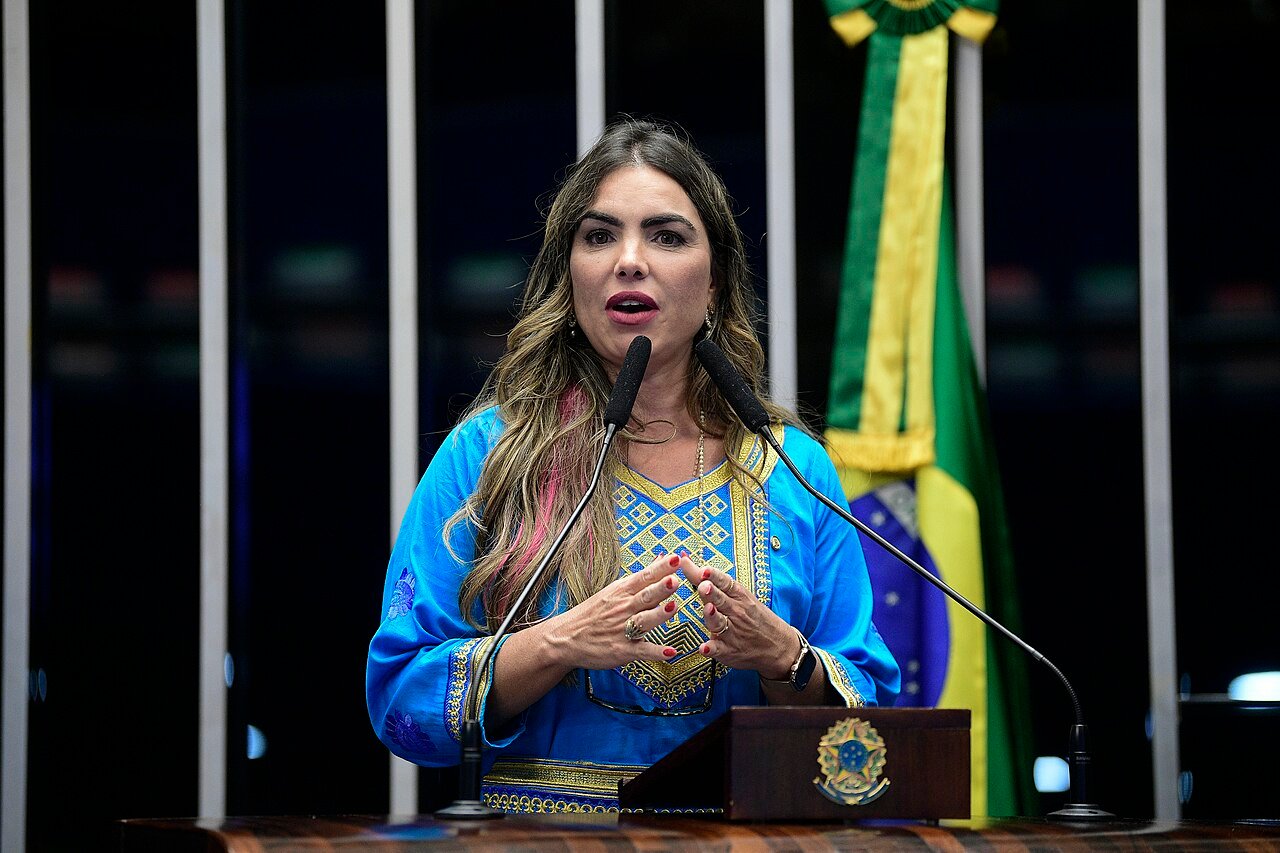 Paula Belmonte discursa em tribuna ao lado da bandeira do Brasil