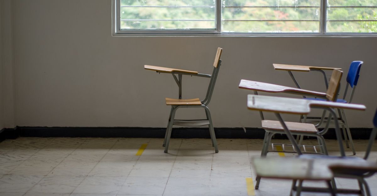 Sala de aula vazia com carteiras escolares de madeira perto de janela ampla
