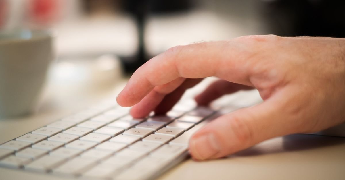 Mão digita em teclado de computador em close