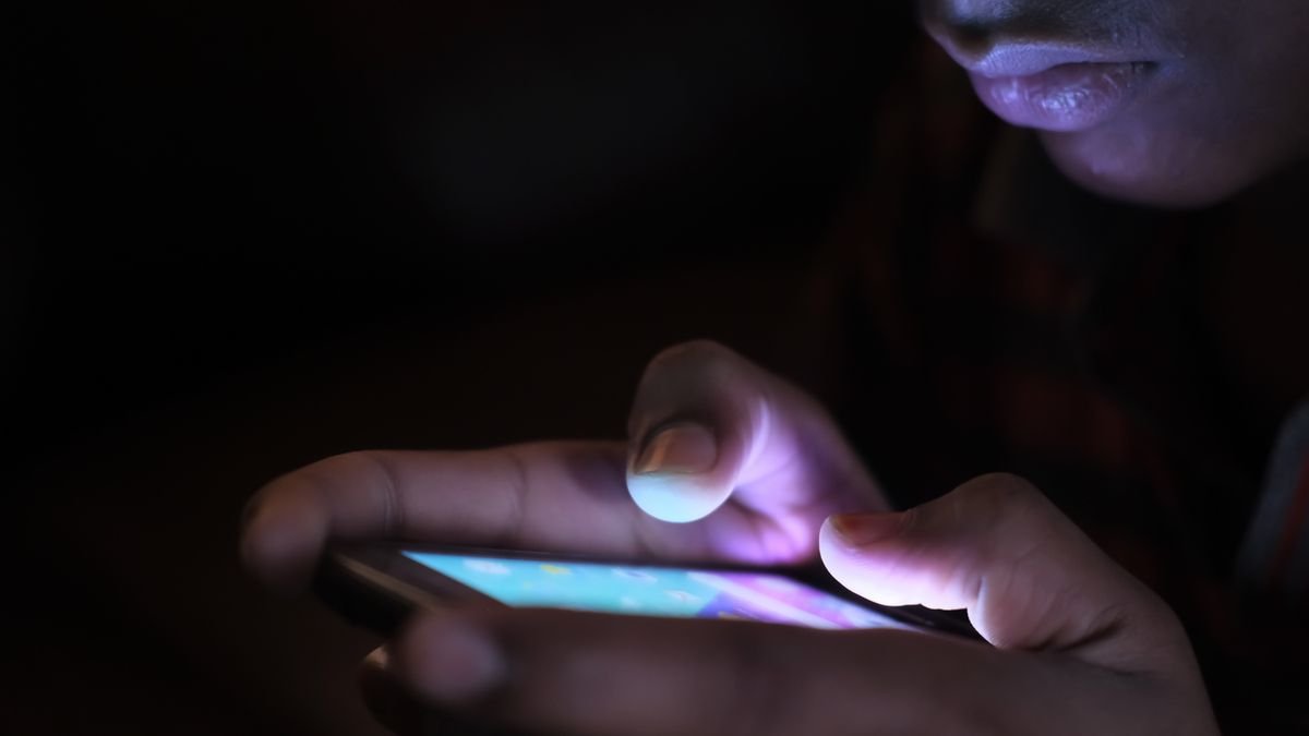Pessoa usa smartphone no escuro com a tela iluminada