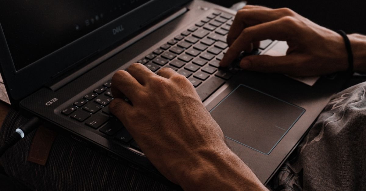 Mãos digitando no teclado de um notebook em ambiente escuro, em imagem ilustrativa sobre crime cibernético
