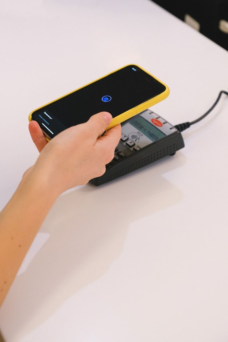 Mão segura celular para pagamento por aproximação em maquininha de cartão