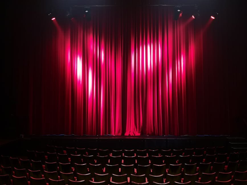 Palco de teatro iluminado com cortinas vermelhas