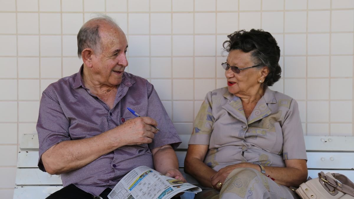 Casal de idosos conversando em um banco; imagem ilustrativa sobre o Meu INSS