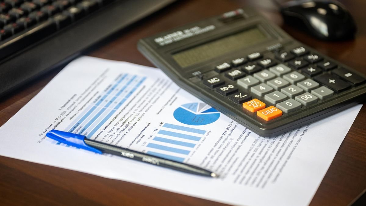 Calculadora e relatório financeiro sobre a mesa; imagem ilustrativa sobre contracheque