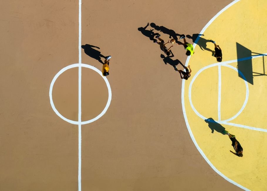Quadra de basquete com jogadores em movimento durante partida