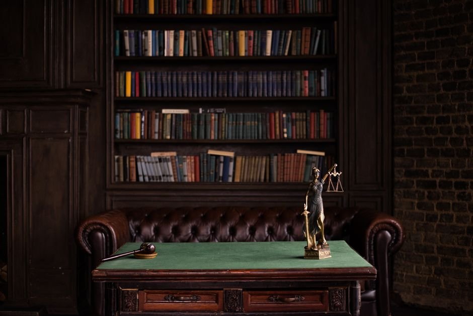 Estatua da justica com balanca e martelo sobre mesa