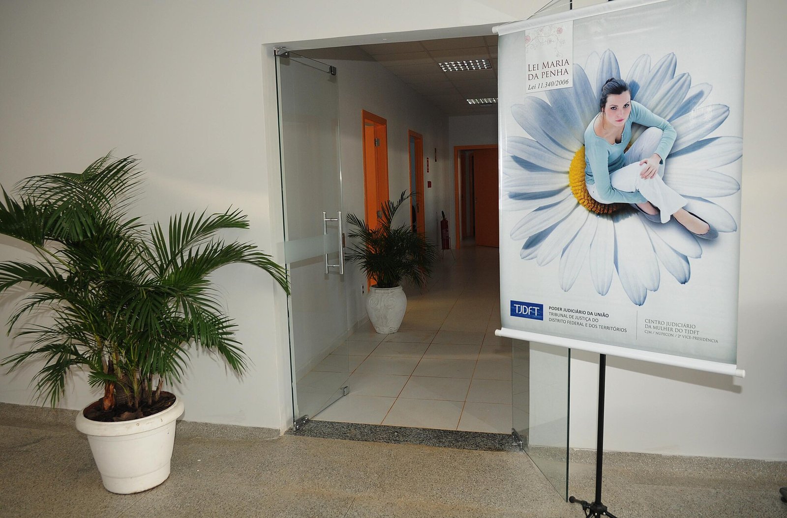 Entrada do Centro Judiciário da Mulher do TJDFT, com banner da Lei Maria da Penha ao lado da porta