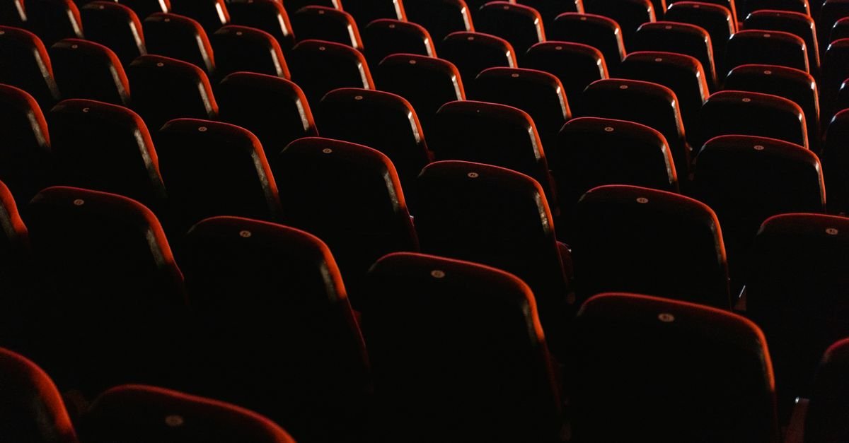 Fileiras de poltronas vermelhas vazias em sala de cinema