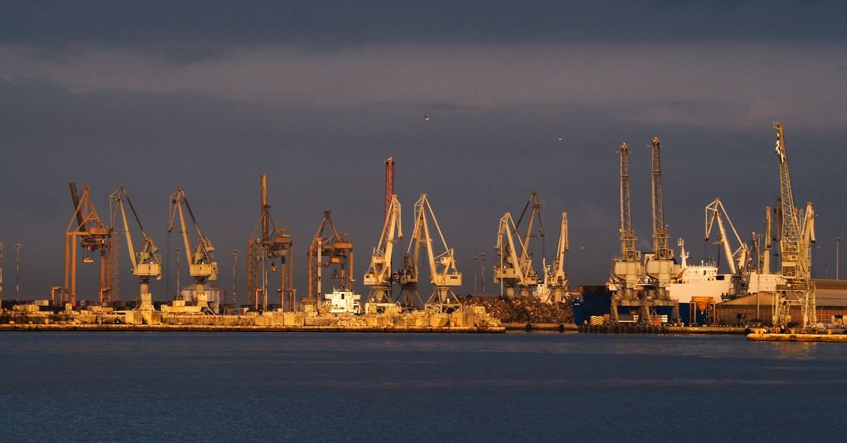 Guindastes e navios em porto de carga ao entardecer