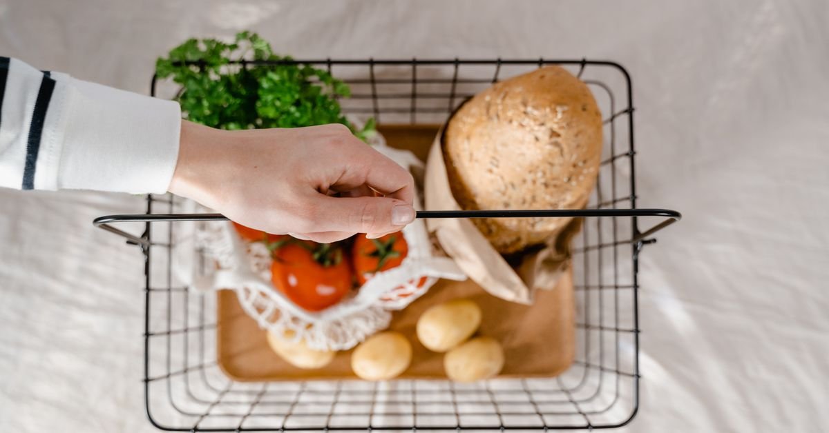 Cesta de compras com pão, tomates, batatas e verduras