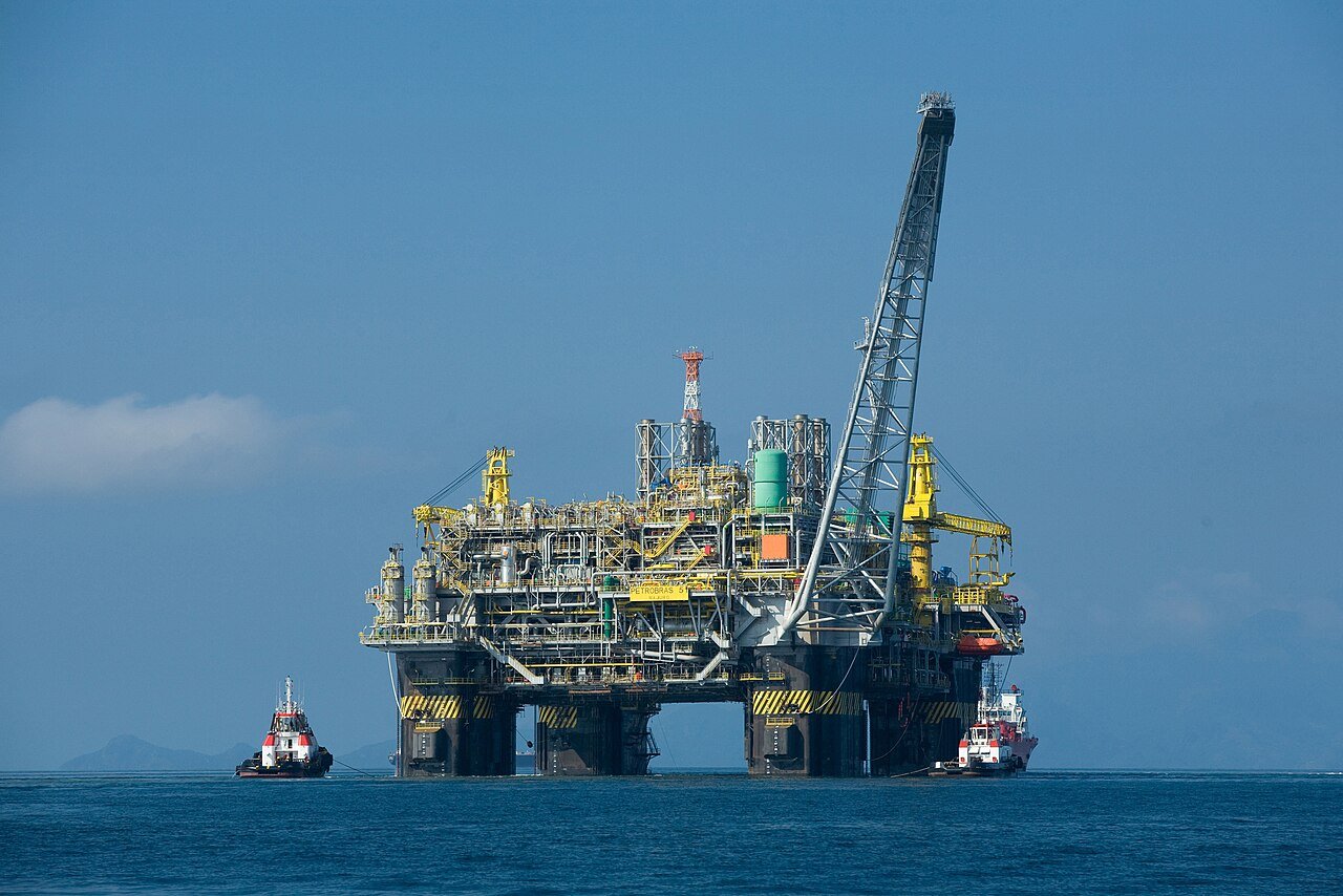 Plataforma de petroleo da Petrobras em operacao no mar, com rebocadores ao lado