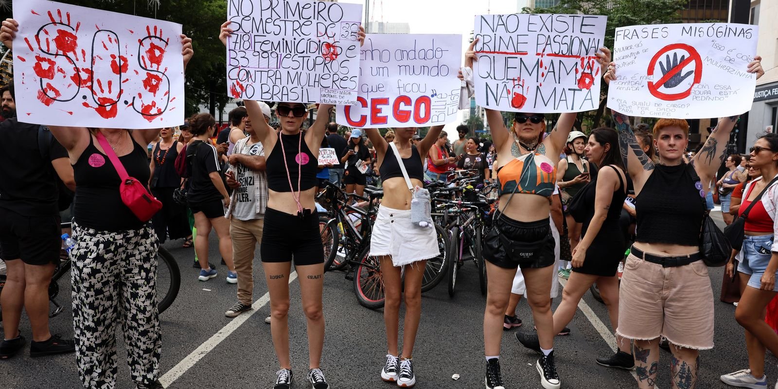 Mulheres erguem cartazes contra a violência de gênero em ato de rua no Brasil