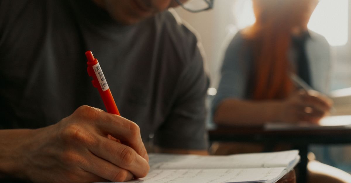Estudante escreve com caneta durante aula