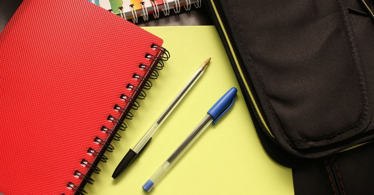 Cadernos coloridos, canetas e estojo escolar sobre uma mesa