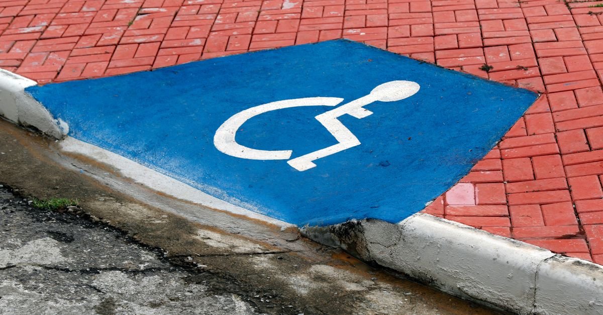 Rampa de acessibilidade pintada de azul com o símbolo internacional de pessoa com deficiência na calçada