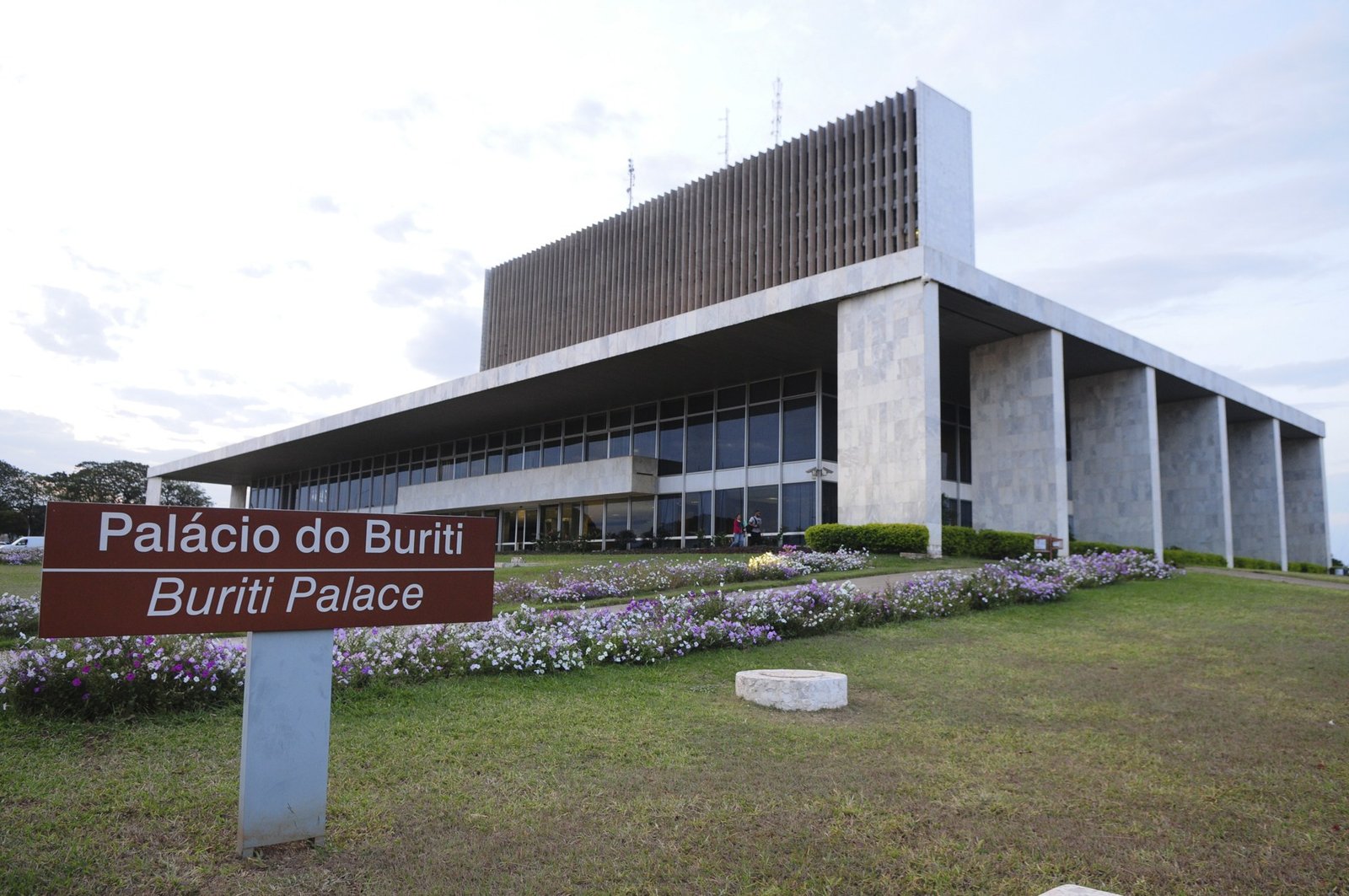Fachada do Palácio do Buriti, sede do governo do Distrito Federal, com a placa de identificação e canteiro de flores em primeiro plano