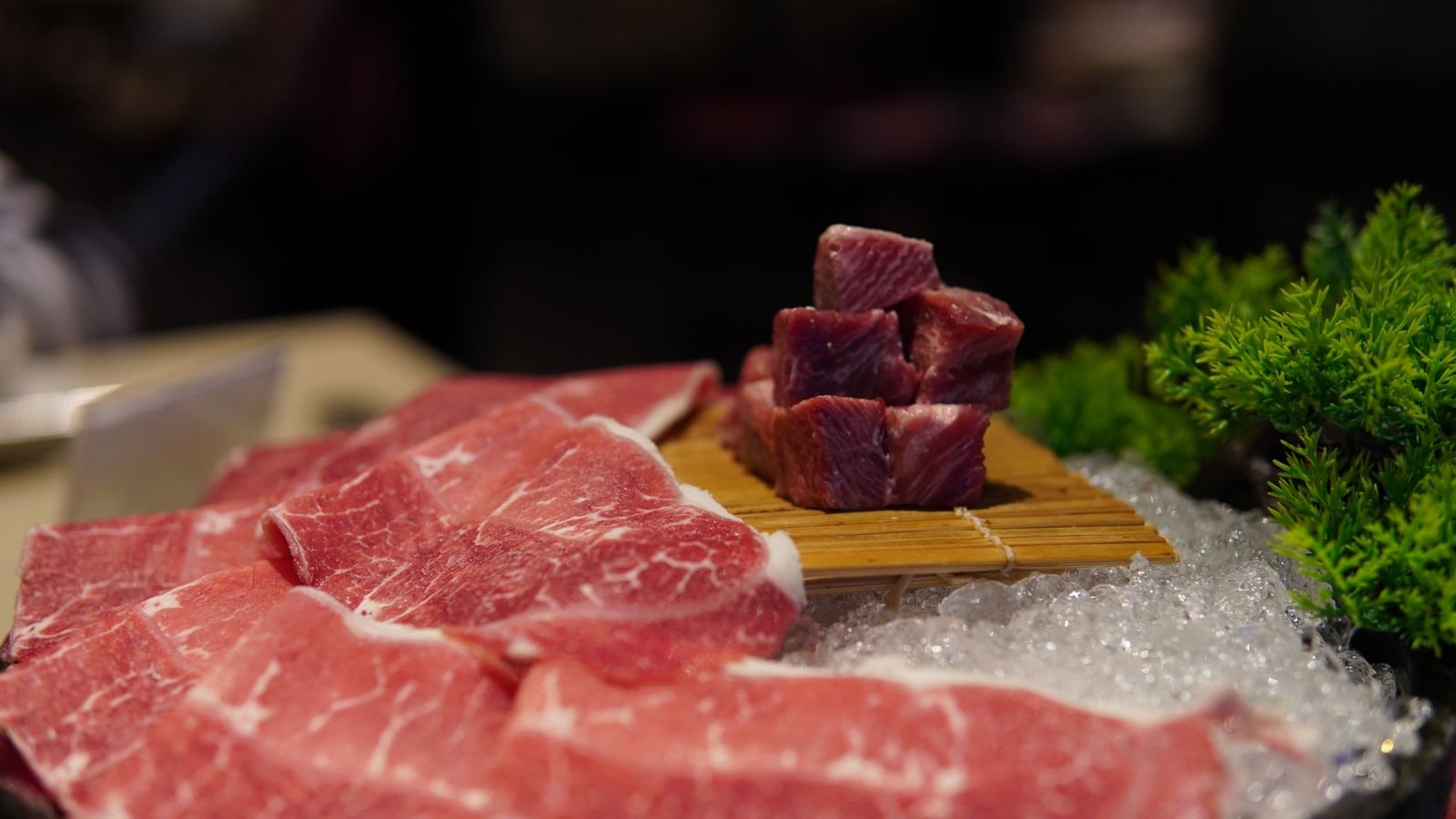Cubos de carne bovina crua sobre esteira de bambu, ao lado de fatias de carne sobre gelo (foto ilustrativa)