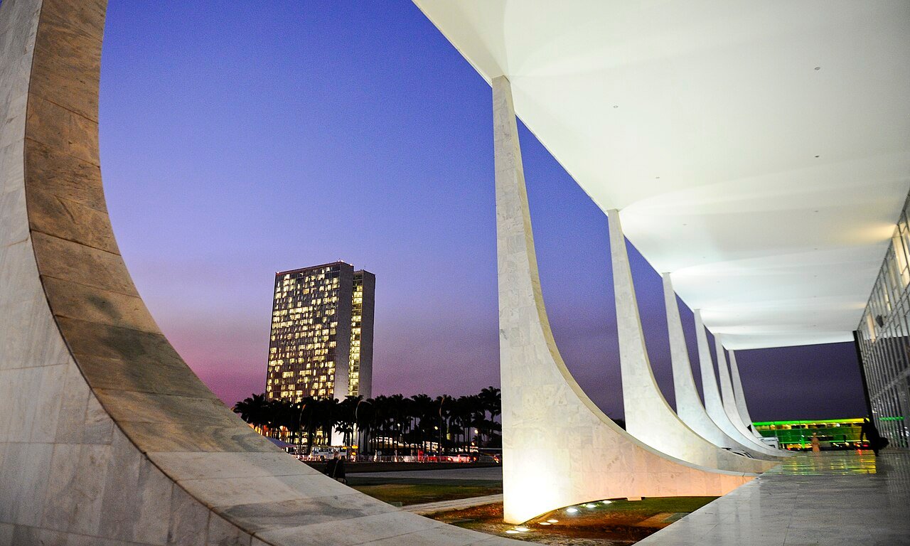 Colunata do Congresso Nacional ao anoitecer, com o edifício anexo iluminado ao fundo
