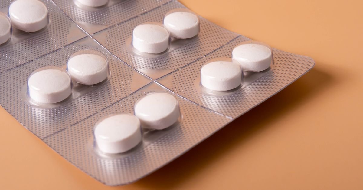 Cartela de comprimidos brancos em embalagem blister sobre fundo neutro