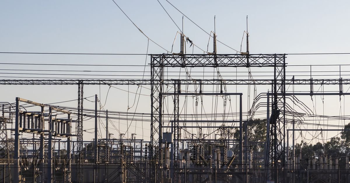 Estruturas metálicas, cabos e equipamentos de alta tensão de uma subestação de energia elétrica ao amanhecer
