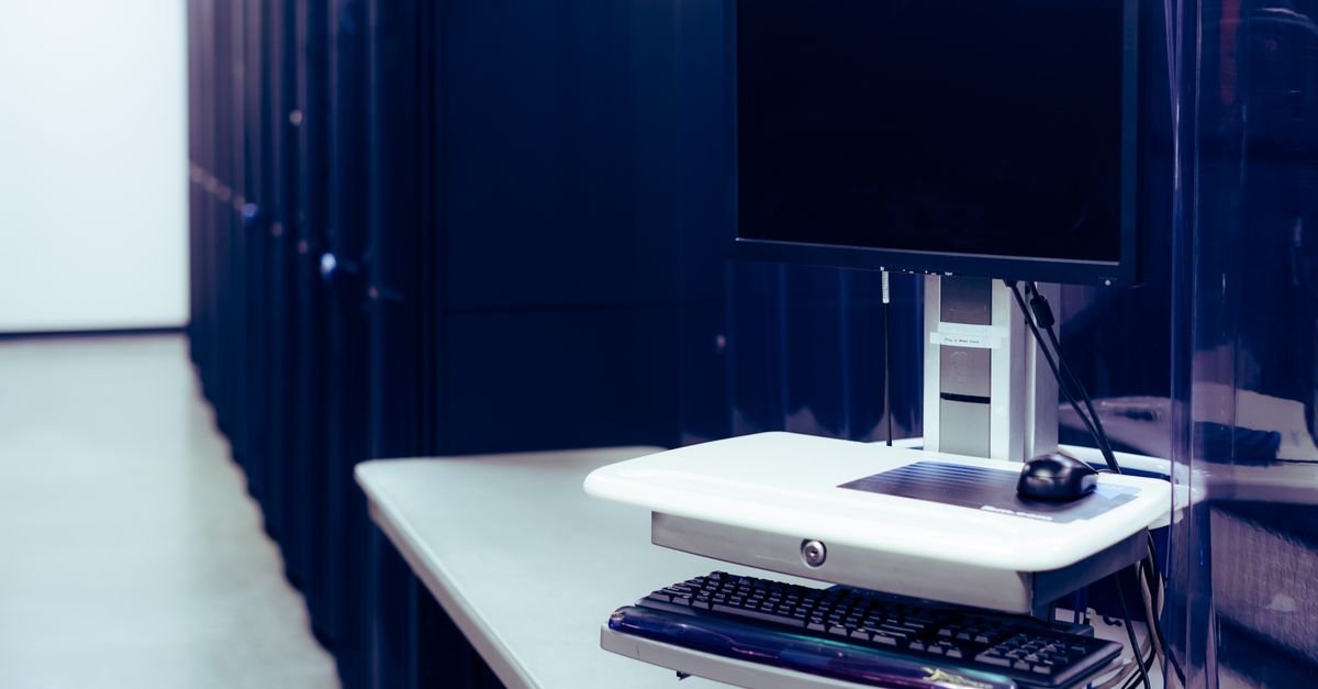 Corredor de data center com racks de servidores e terminal de operação