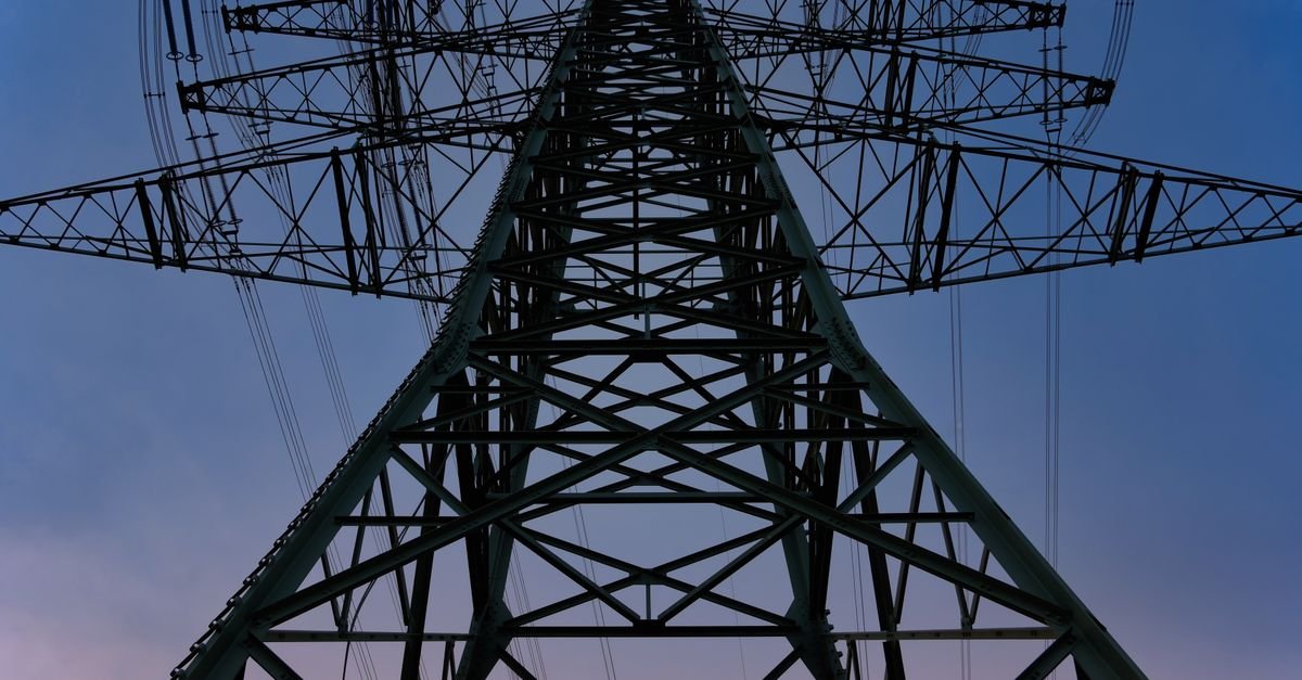 Torre metalica de transmissao de energia fotografada de baixo contra ceu no fim da tarde