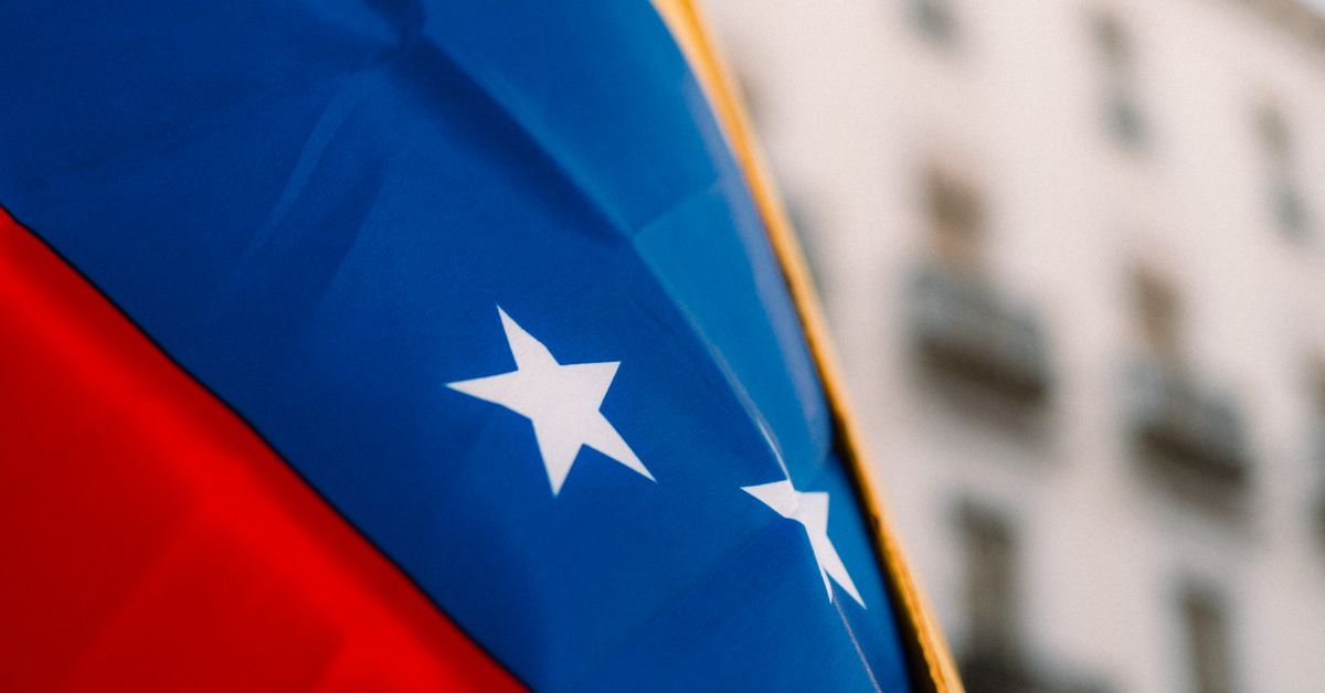 Bandeira da Venezuela em primeiro plano com prédio ao fundo