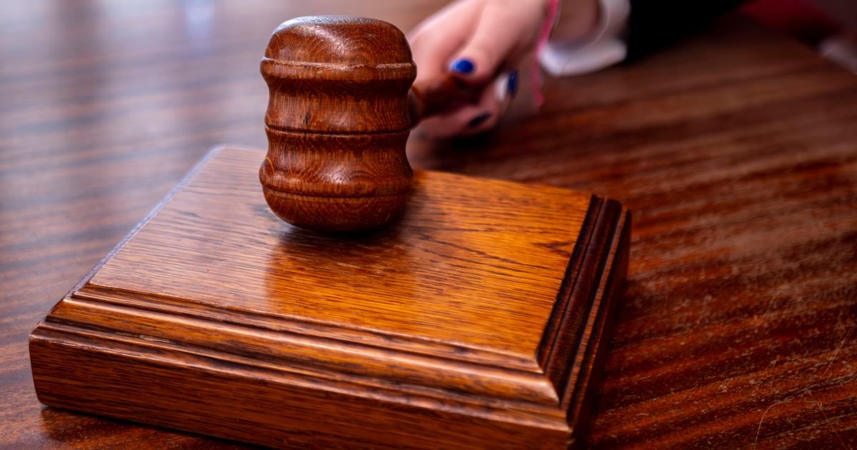 Martelo de juiz sobre bloco de madeira em mesa de tribunal