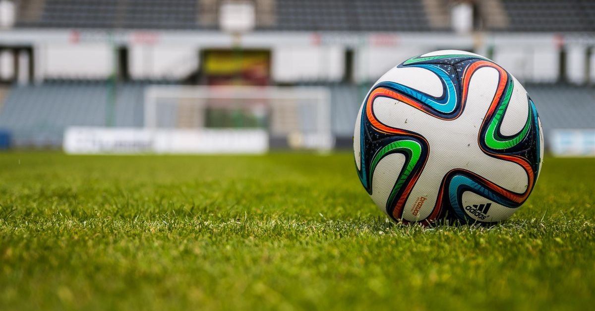 Bola de futebol parada no gramado de um estádio vazio