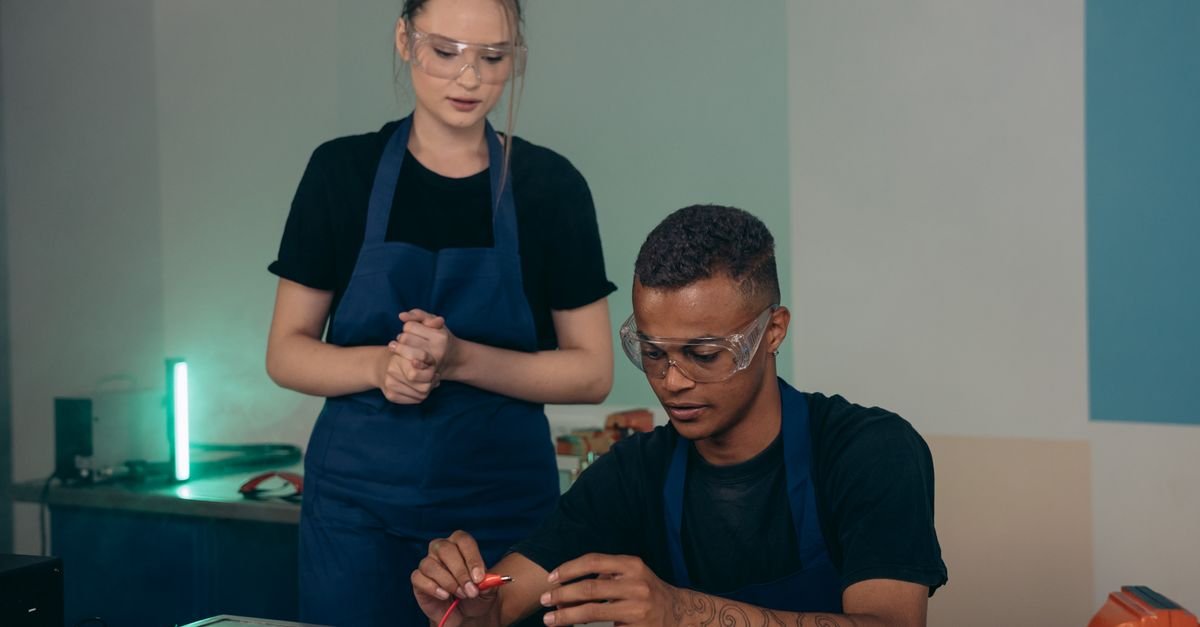 Estudantes com óculos de proteção trabalham com componentes eletrônicos em laboratório