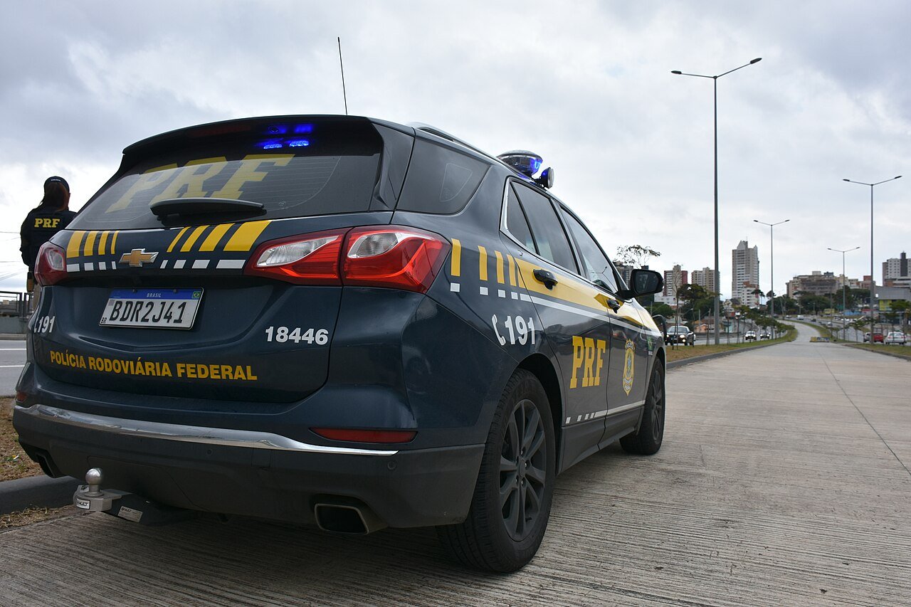 Viatura da Polícia Rodoviária Federal parada no acostamento de uma via, vista pela traseira