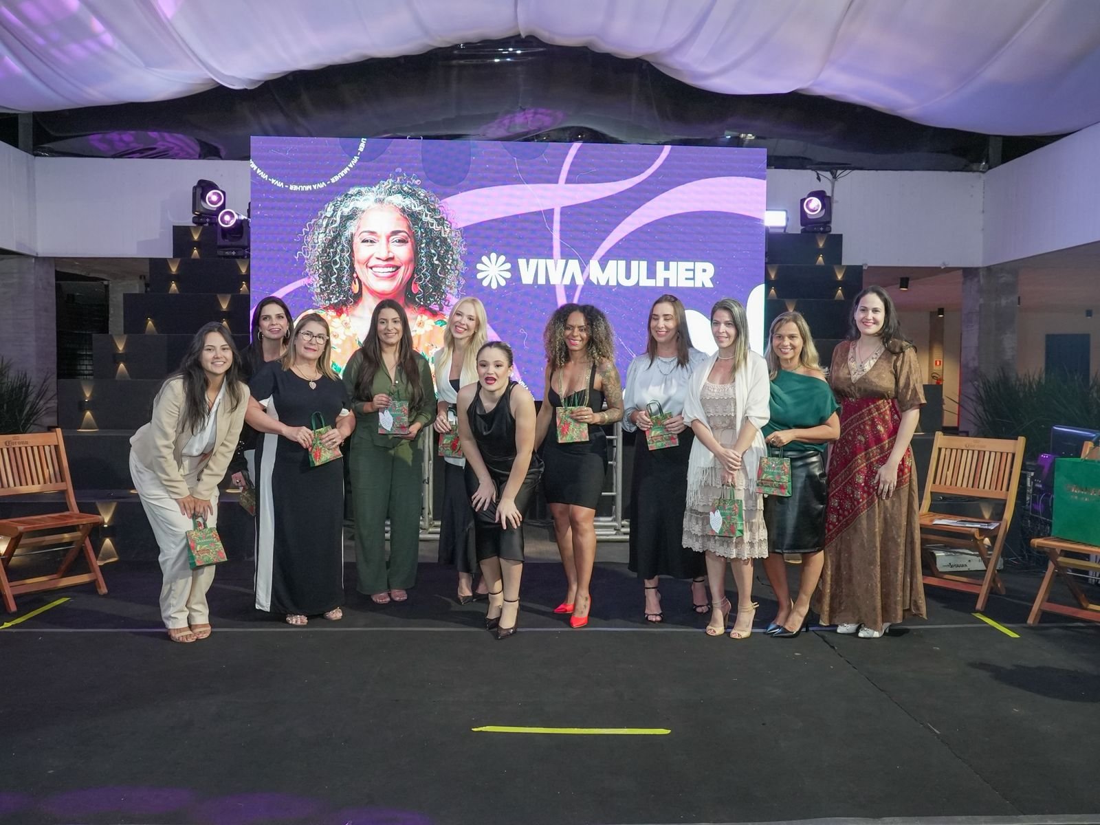 Equipe do Viva Mulher posa para foto durante evento de lancamento com backdrop oficial do projeto