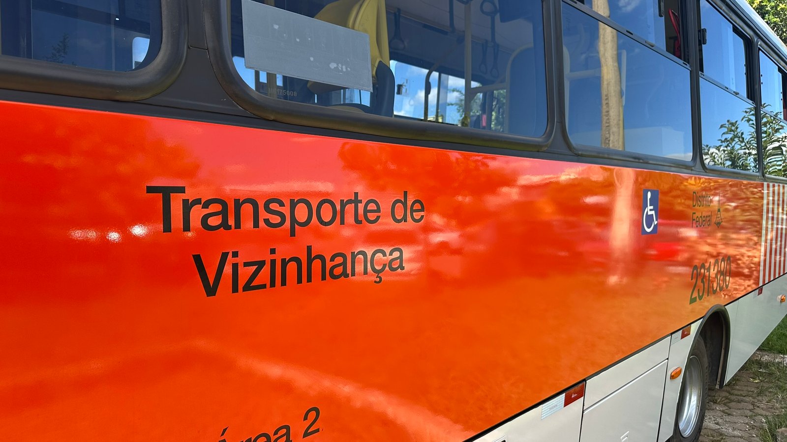 Lateral laranja de um ônibus zebrinha do Distrito Federal com a inscrição Transporte de Vizinhança e o símbolo de acessibilidade
